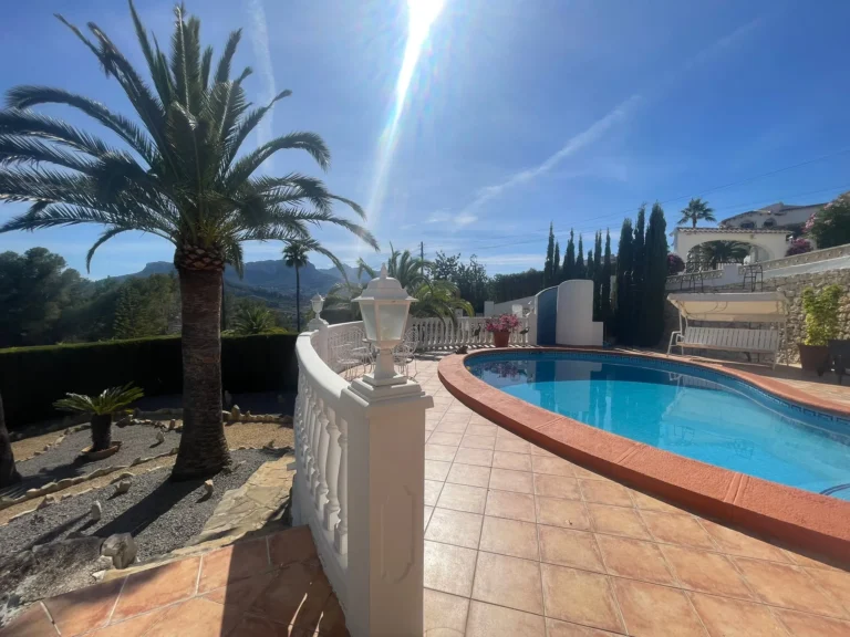 Private pool terrace with mountain views, palm trees, and outdoor seating at a villa in Calpe.