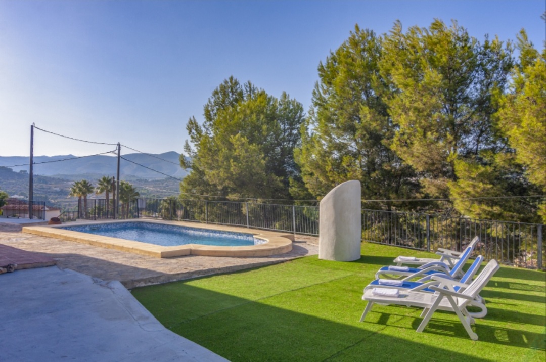 Private swimming pool and garden with sun loungers and mountain views at a Mediterranean villa in Calpe.