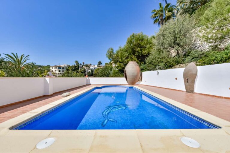 Private swimming pool at a charming Benissa Coast villa with outdoor shower, tiled terrace, white garden walls and Mediterranean greenery