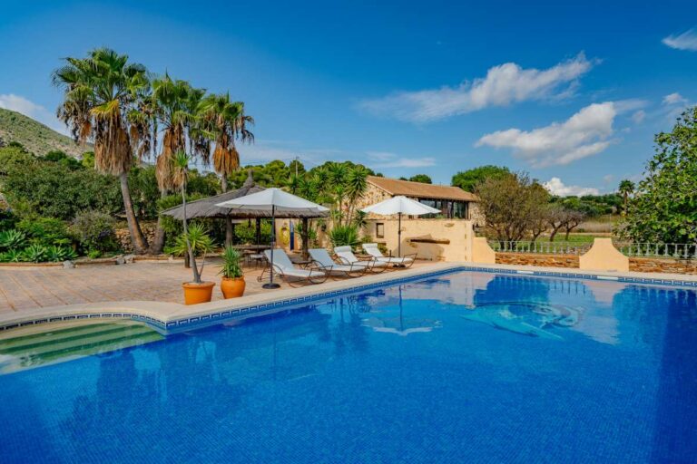 Private swimming pool at a historic luxury finca in Benissa with sun terrace, loungers, parasols and Mediterranean garden surroundings