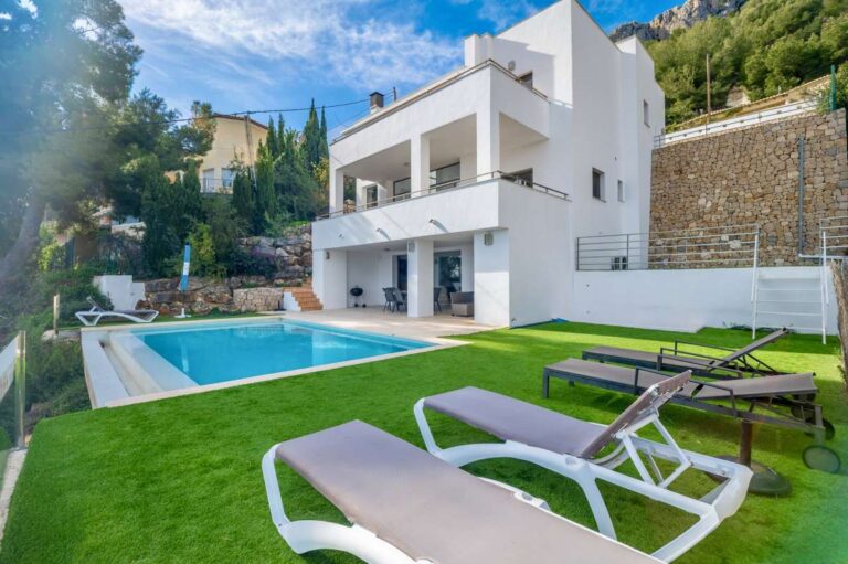 Private swimming pool with garden area and sun loungers at a modern spacious villa in Calpe.