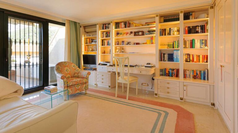Reading room inside a luxury apartment in Sierra de Altea with built-in shelving, armchair, marble flooring and terrace access