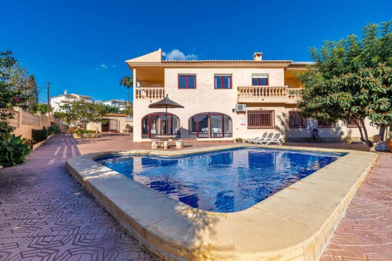 Rectangular swimming pool with terrace and exterior view of a spacious villa with guest apartments in Calpe.