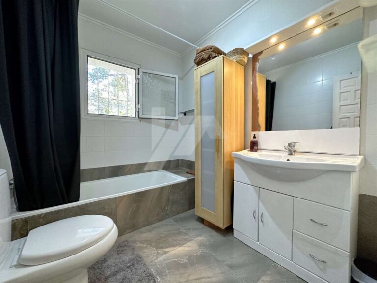 Renovated bathroom inside a single-level villa near El Portet Beach in Moraira with bathtub, vanity unit, toilet and modern tiled finish
