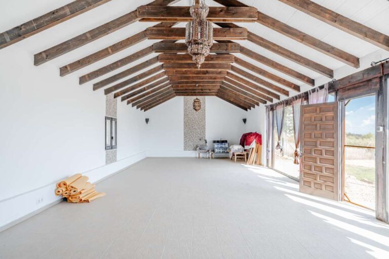 Renovated interior space inside a historic finca in Benissa with exposed wooden beams, white walls, natural light and traditional roof structure