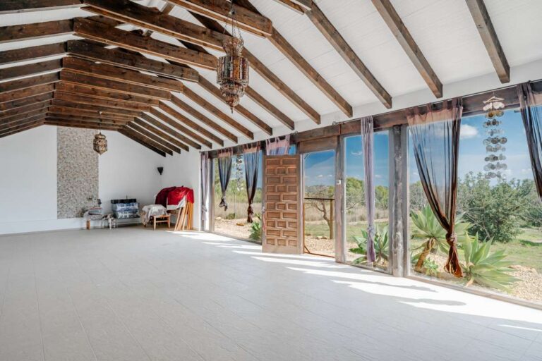 Renovated open interior inside a historic finca in Benissa with exposed wooden beams, large windows and countryside views