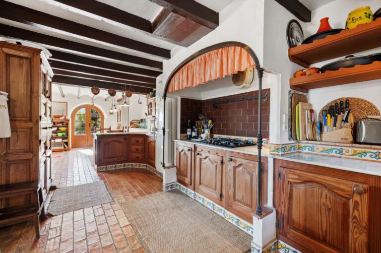 Rustic kitchen inside a traditional Spanish finca near Moraira with wooden cabinetry, tiled worktops, beamed ceiling and Mediterranean character