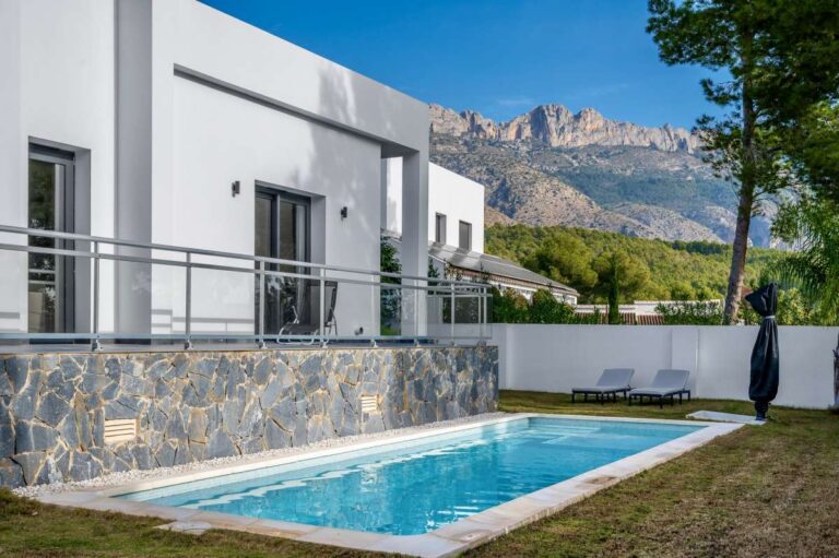 Saltwater swimming pool at a single-level modern villa in Santa Clara, Altea with white exterior, mountain views, glass railing and private garden