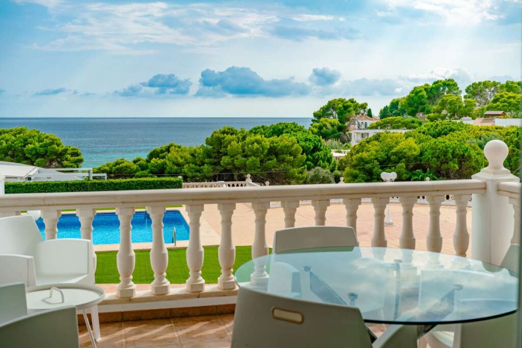 Sea view terrace at a duplex apartment near Les Platgetes Beach in Moraira with outdoor dining area, communal pool views and Mediterranean coastline beyond