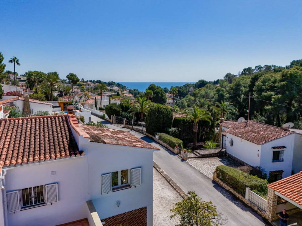Sea views from a charming Benissa Coast villa with surrounding homes, Mediterranean greenery and coastline in the distance