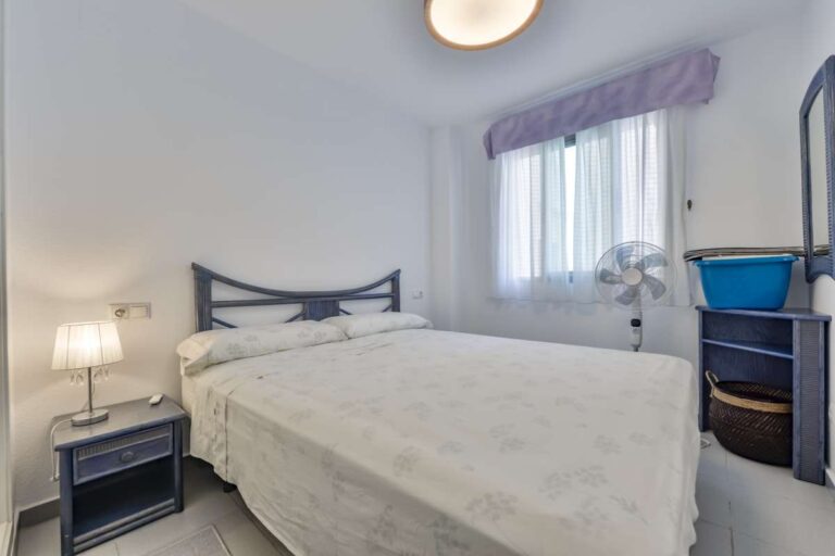 Second bedroom inside a beachfront apartment in La Fossa, Calpe with window, bedside table and natural light