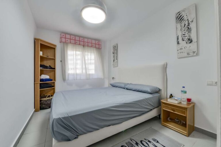 Second bedroom inside a La Fossa beachfront apartment in Calpe with window, bedside table and storage shelving