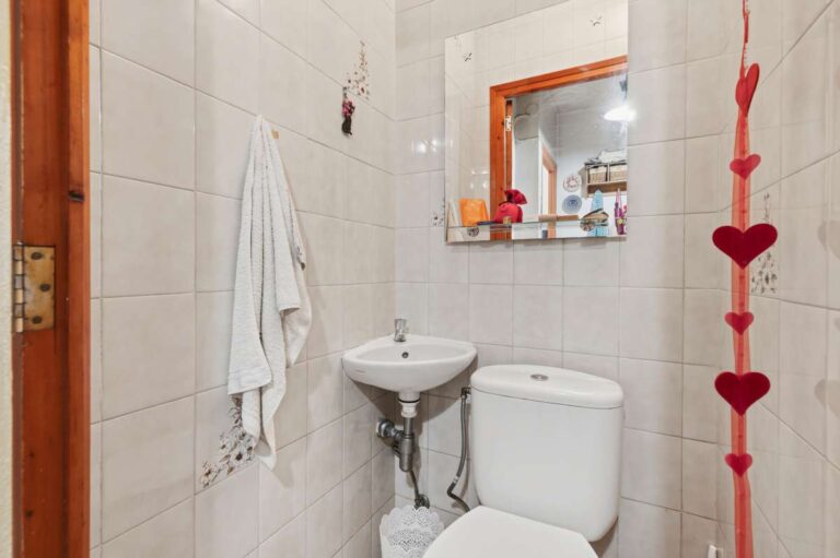 Separate toilet inside a Mediterranean villa in Benissa Costa with small basin, mirror, tiled walls and simple layout