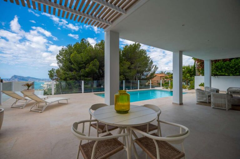Shaded poolside terrace at a modern villa in Altea Hills with outdoor dining area, private swimming pool, sun loungers and sea views