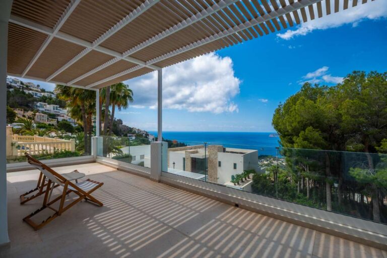 Shaded terrace at a modern villa in Altea Hills with pergola, outdoor seating, glass railing, sea views and mountain views