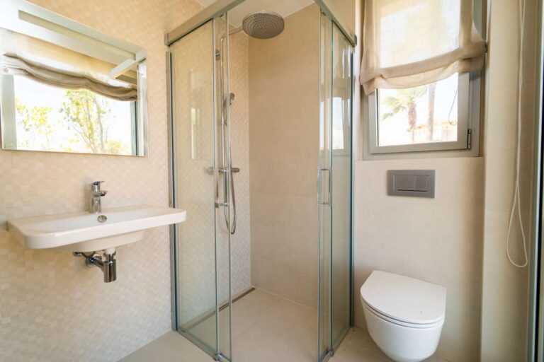 Shower room inside a luxury villa in Calpe with glass shower screen, wall-mounted basin, toilet and natural light