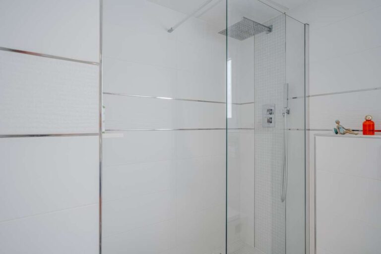 Shower room inside a renovated apartment by Arenal-Bol Beach in Calpe with glass shower screen and bright white tiled finish