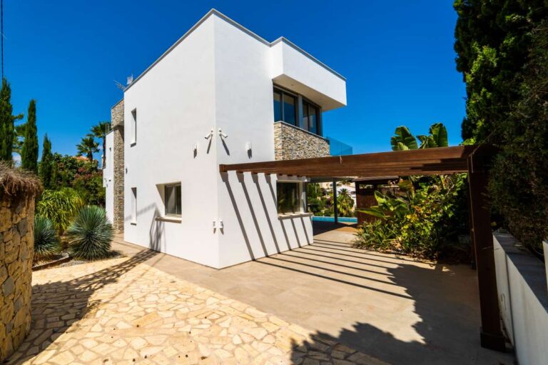 Side exterior of a luxury villa in Calpe with covered terrace, stone walling, modern architecture and private outdoor space