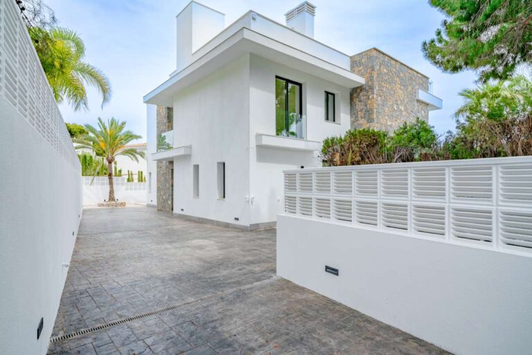 Side exterior of a modern second-line sea villa in La Calalga, Calpe with white façade, private driveway and contemporary design