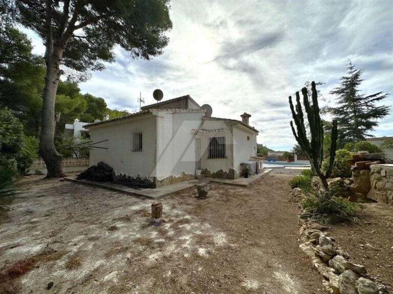 Side exterior of a single-level villa near El Portet Beach in Moraira with garden area, mature trees, cactus planting and private outdoor space