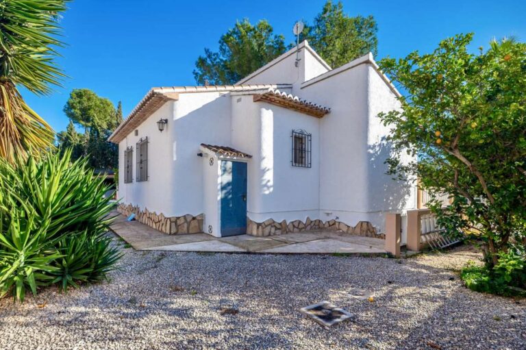 Side exterior of a south-facing single-level villa in Calpe with garden area and Mediterranean planting.