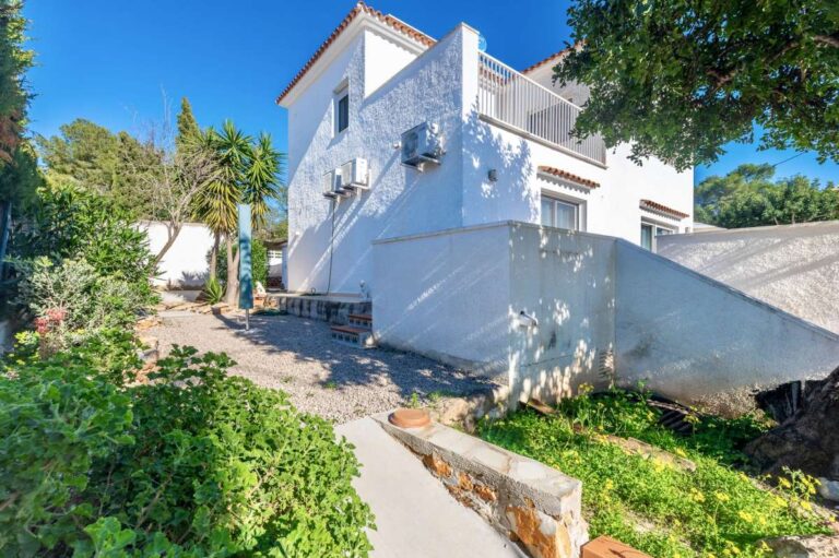 Side garden area with trees and exterior view of a contemporary villa in a peaceful residential area of Calpe.
