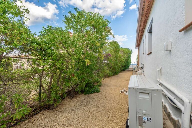Side garden path at a premium coastal villa on the Benissa Costa with gravel walkway, mature hedging and exterior utility area