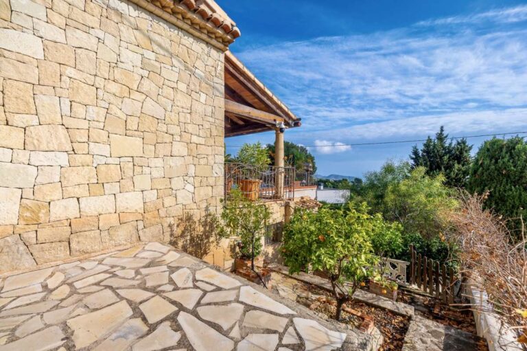 Side terrace at a finca-style villa in Benissa Costa with natural stone exterior, paved walkway, sea views and Mediterranean planting