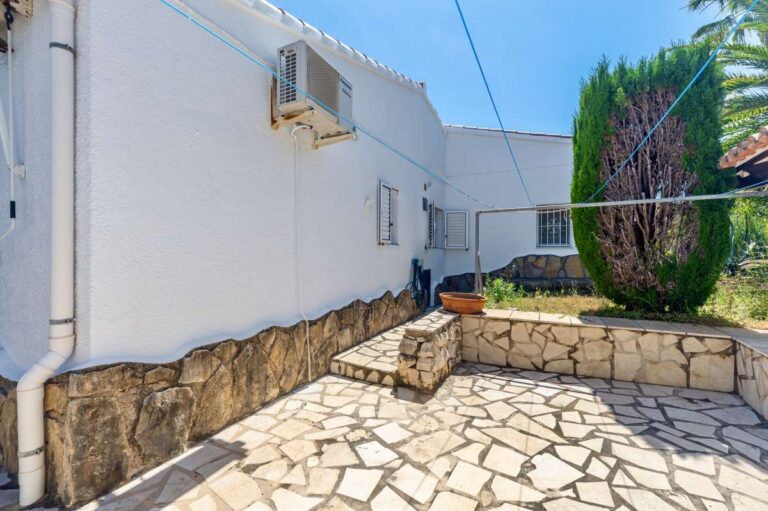 Side terrace at a renovated single-level villa in Moraira with stone paving, exterior access, palm tree and Mediterranean planting