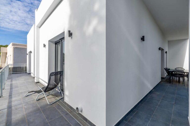 Side terrace at a single-level modern villa in Santa Clara, Altea with tiled flooring, outdoor seating, white exterior walls and garden access
