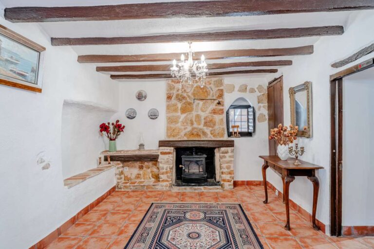 Sitting room inside a historic finca in Benissa with fireplace, wooden beams, chandelier and traditional Mediterranean interior design