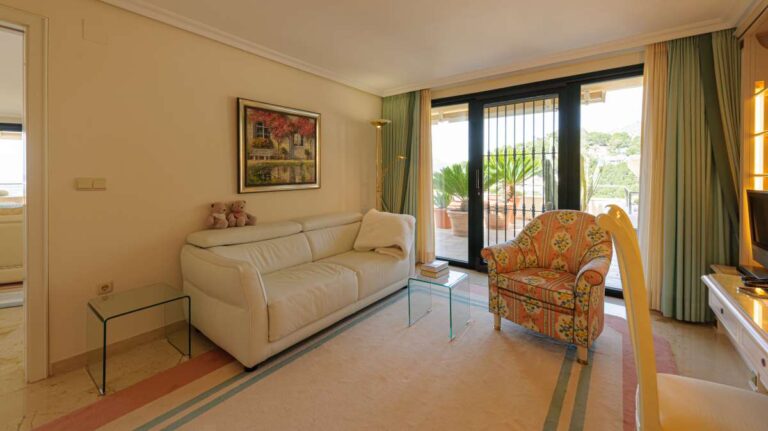 Sitting room inside a luxury apartment in Sierra de Altea with sofa seating, armchair, marble flooring and access to the terrace