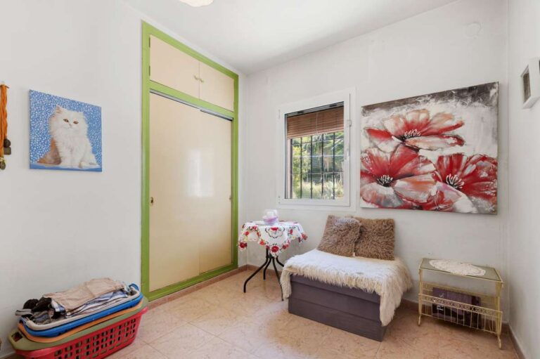 Small sitting room inside a Mediterranean villa in Benissa Costa with armchair, window, wall art and bright white interior finish