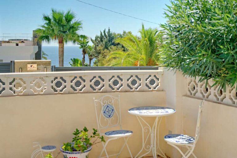 Small terrace seating area with tiled table and greenery at a Mediterranean villa near Puerto Blanco in Calpe.