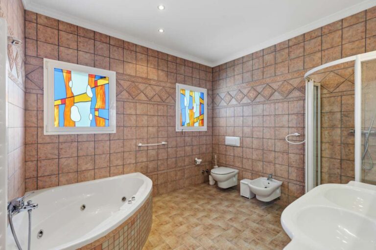 Spacious bathroom with bath, sink, toilet, bidet, and natural light inside a villa in Calpe.