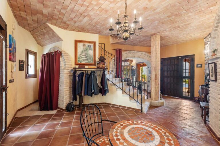 Spacious entrance hall inside a finca-style villa in Benissa Costa with staircase, terracotta tiled floor, arched details and traditional Mediterranean design
