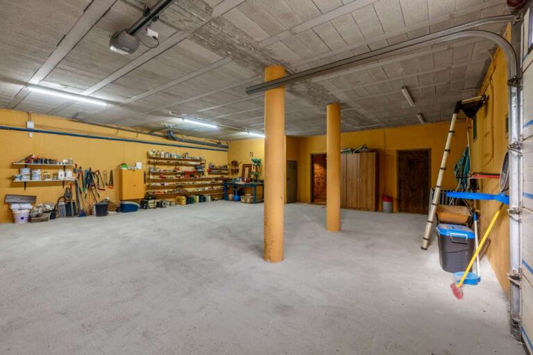 Spacious garage and storage area inside a finca-style villa in Benissa Costa with support columns, shelving, workshop space and concrete floor