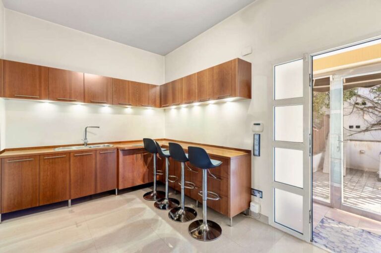 Spacious kitchen inside a private villa in Calpe with wooden cabinetry, breakfast bar and terrace access