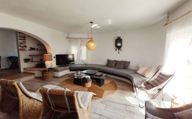 Spacious living room with curved sofa, arched opening and natural light inside a refurbished villa with sea views in Canuta, Calpe.