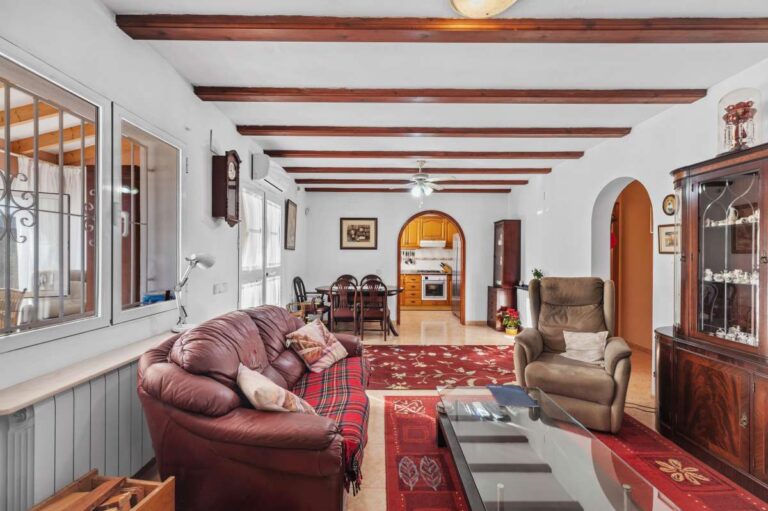 Spacious living room with fireplace, dining area and natural light inside a single-level villa for sale in Calpe.
