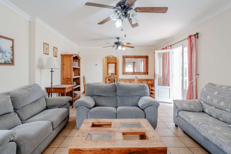 Spacious living room with sofa seating, ceiling fan and traditional furniture inside a Mediterranean villa with independent guest accommodation in Calpe.