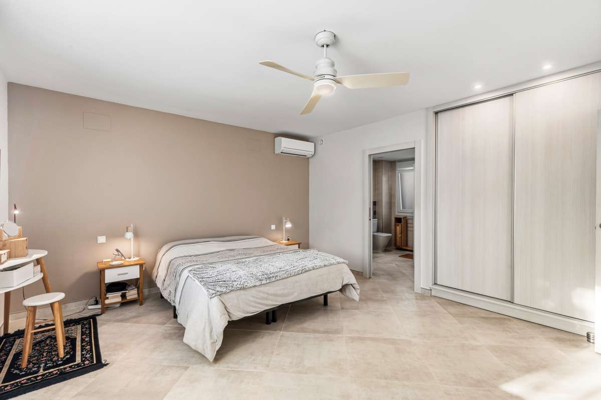 Spacious master bedroom with fitted wardrobes, air conditioning and ceiling fan inside a contemporary villa in Calpe.