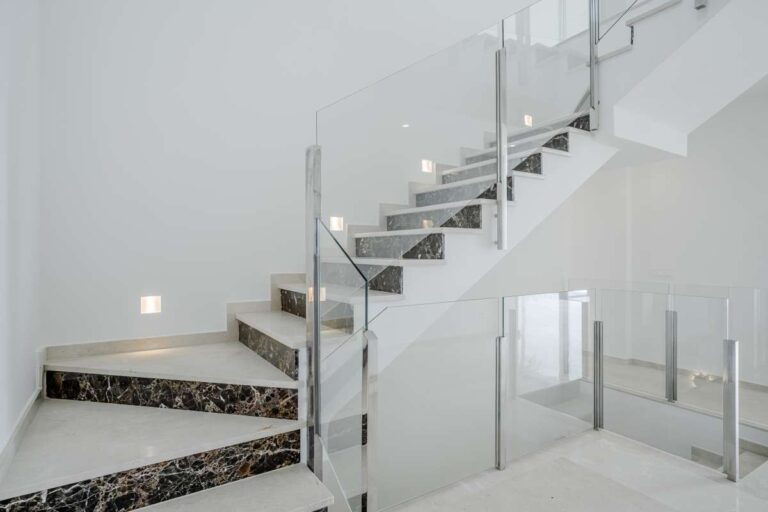 Staircase detail inside a modern second-line sea villa in La Calalga, Calpe with glass balustrade and bright contemporary finish