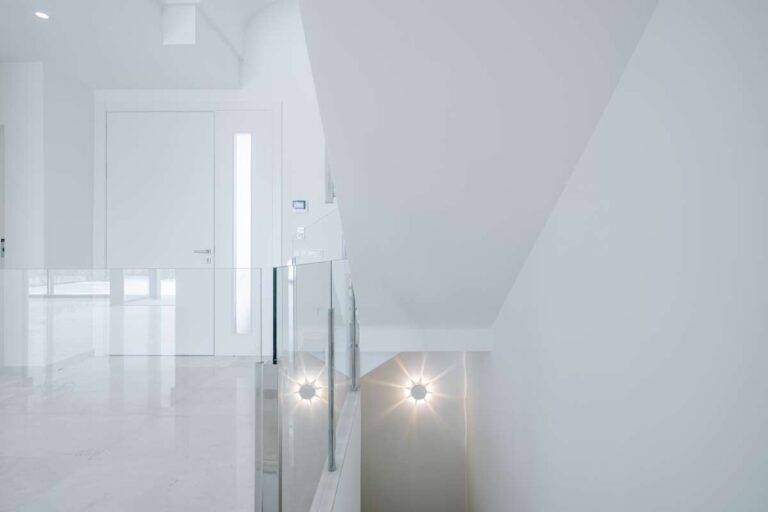 Stairwell detail inside a modern second-line sea villa in La Calalga, Calpe with glass balustrade, bright walls and integrated lighting