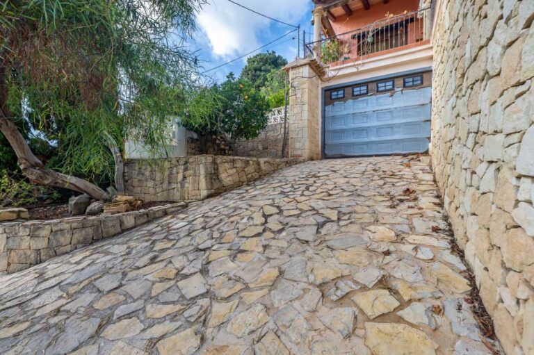Stone driveway at a finca-style villa in Benissa Costa with private garage, natural stone walls, paved access and mature garden surroundings