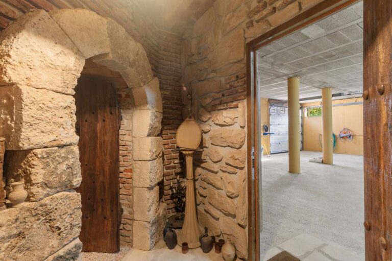 Stone entrance inside a finca-style villa in Benissa Costa with arched doorway, rustic stone walls, wooden door and access to the lower level