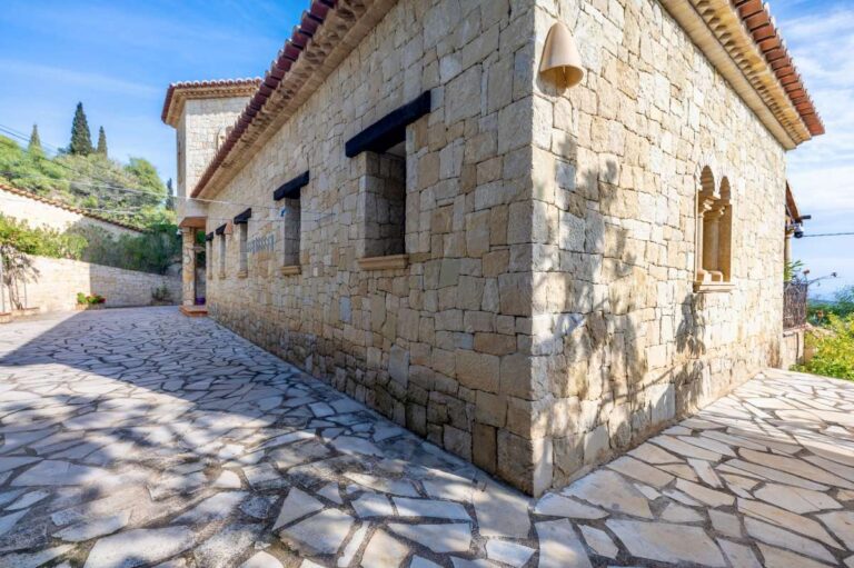 Stone exterior of a finca-style villa in Benissa Costa with rustic Mediterranean architecture, paved driveway and surrounding greenery