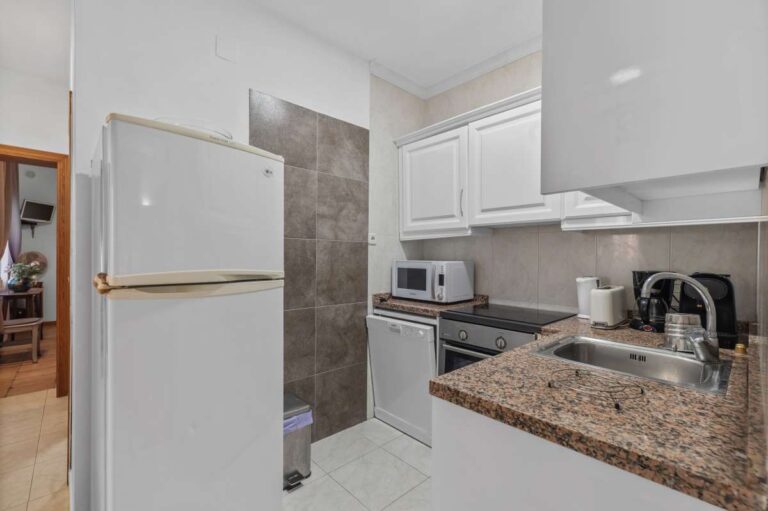 Studio kitchen inside an independent living area of a Benissa villa with white cabinetry, fridge, sink and compact cooking space