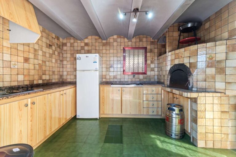 Summer kitchen with stone BBQ area and fitted cabinets at a spacious villa with guest apartments in Calpe.