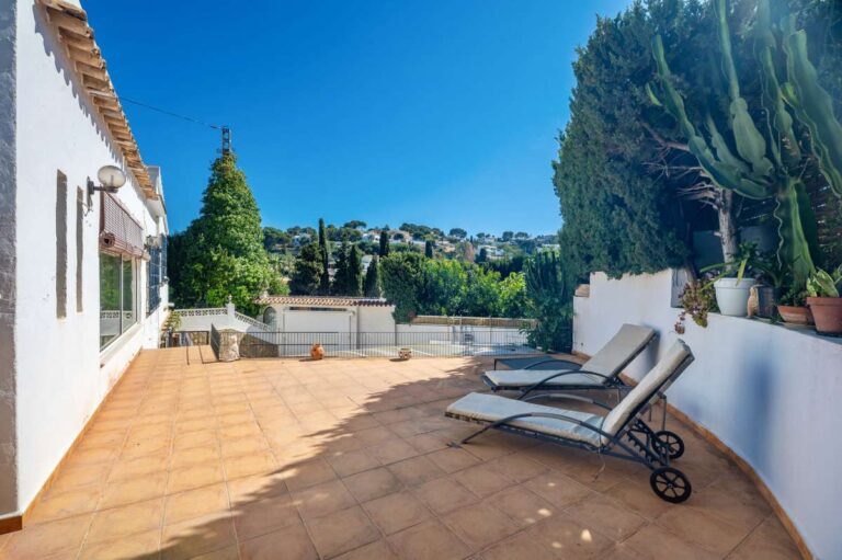 Sun terrace at a Mediterranean villa in Benissa Costa with sun loungers, tiled outdoor space and mature garden surroundings